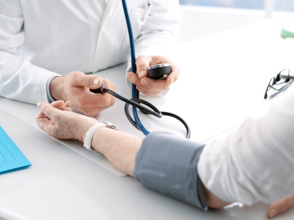 Professional doctor measuring blood pressure of a senior female patient during a visit, hypertension and prevention concept